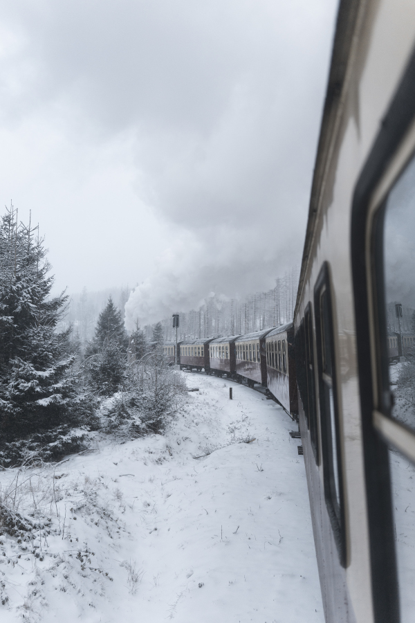 View outside of an old steam train going up a snowy landscape